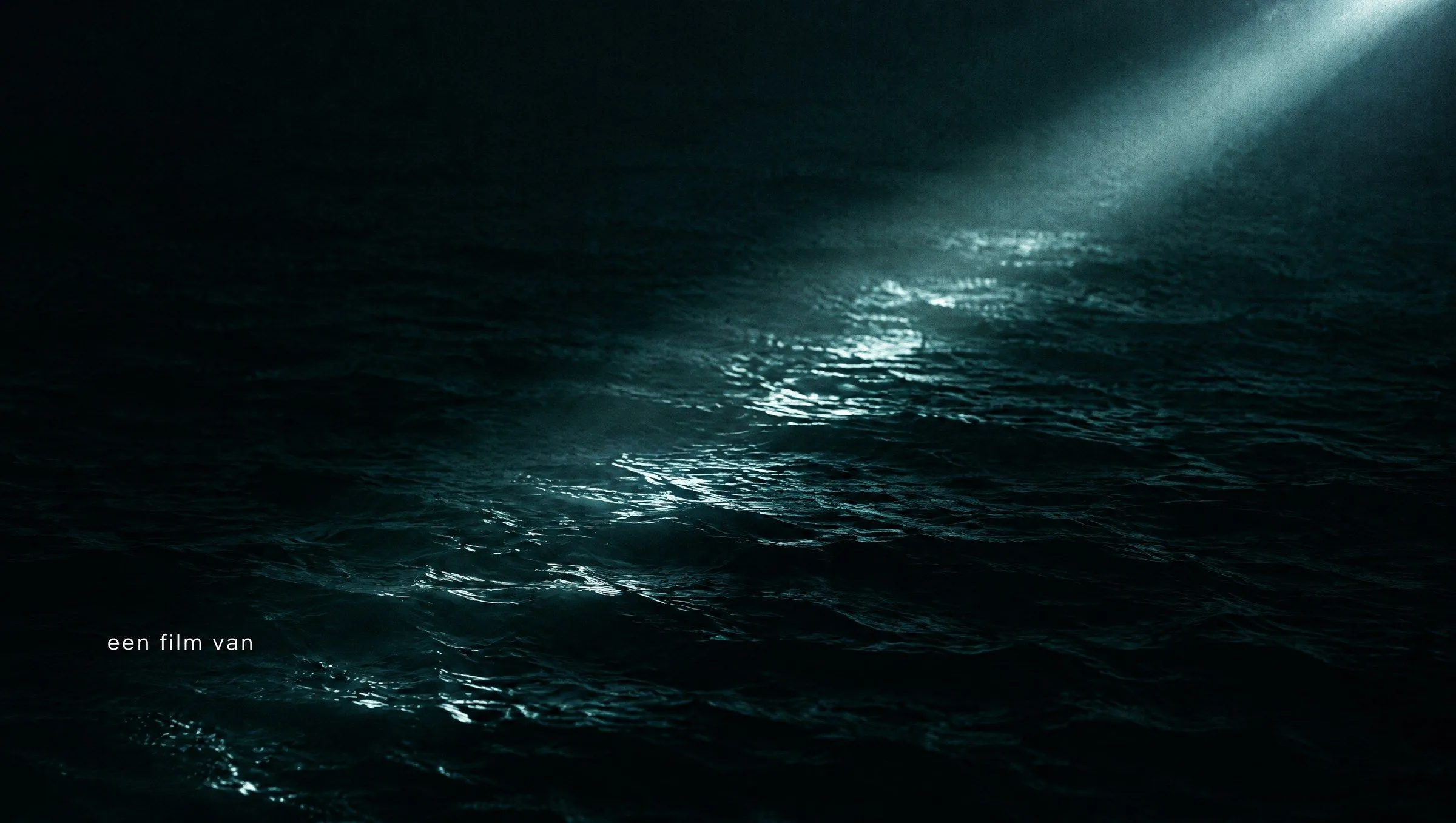 Een klein wit credit over donker rimpelend water met één diagonale lichtbundel.