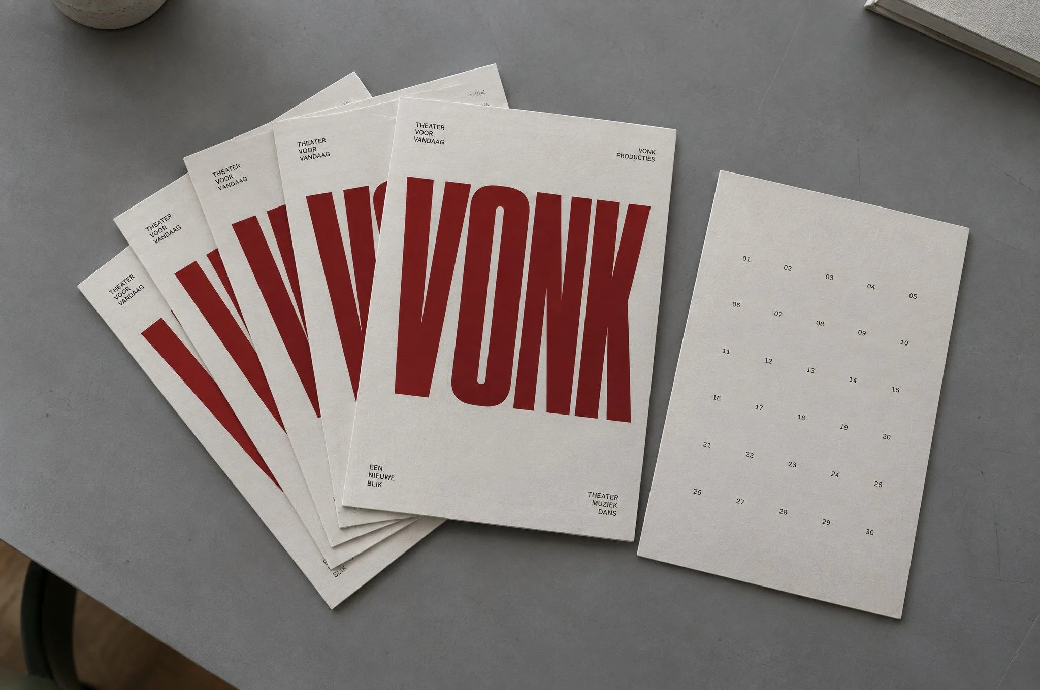 Een waaier flyers met het woord VONK en een kaart met een raster van data op een grijze tafel.